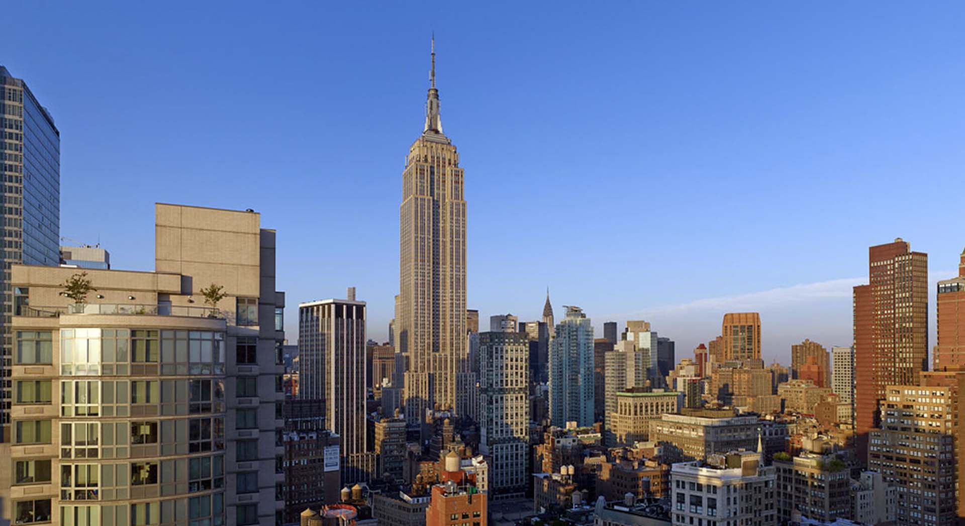 rooftop view of manhattan looking uptown during the day with clear skies and empire state building
