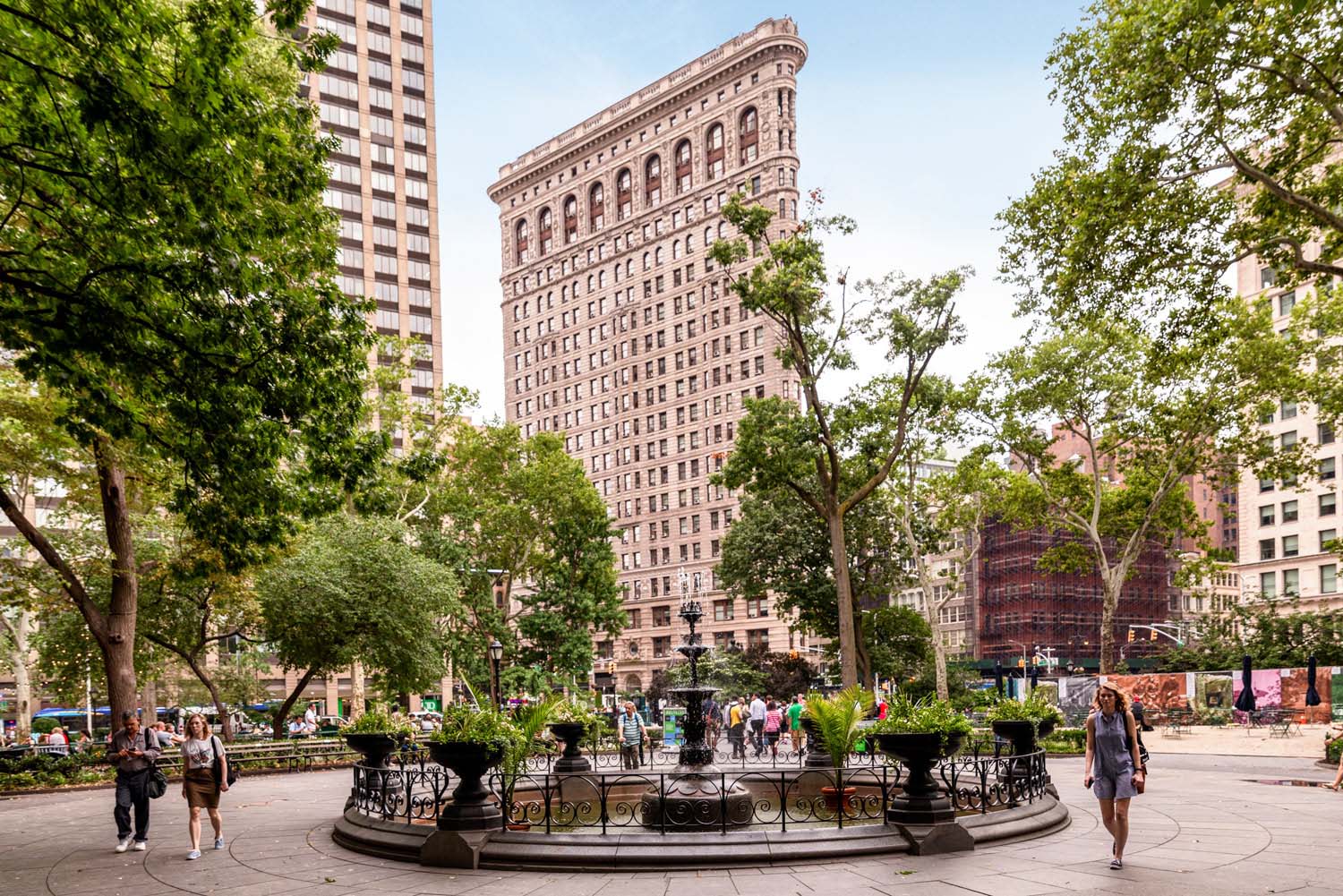 New York city park with fountain during the day with people walking and the flatiron building behind