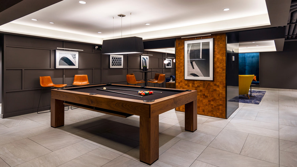 Game lounge with black felt pool table and marble floors, black walls, and art deco wood detailing